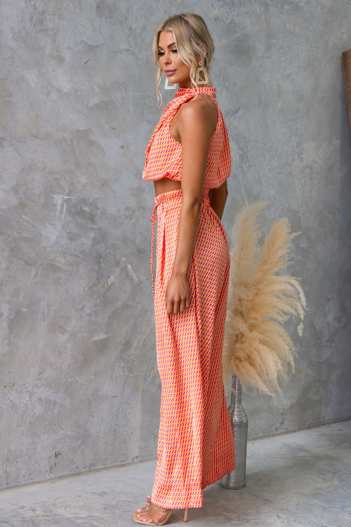 Model showcasing the Dreamie Set in coral, featuring a sleeveless top and mid-high waist pants with a tie.