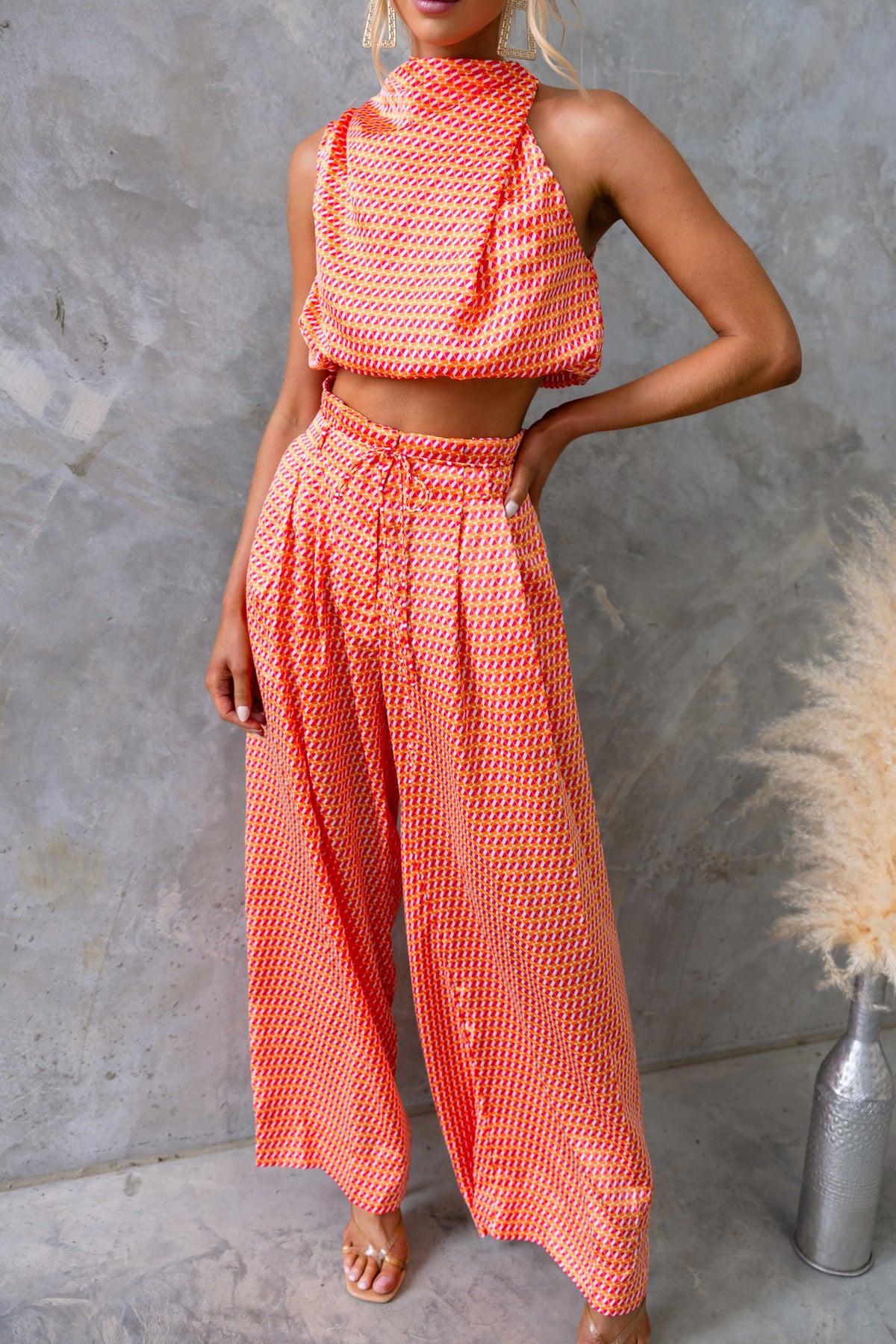 Stylish Dreamie Set featuring a high neckline crop top and mid-high waist pants in vibrant orange with a satin look.