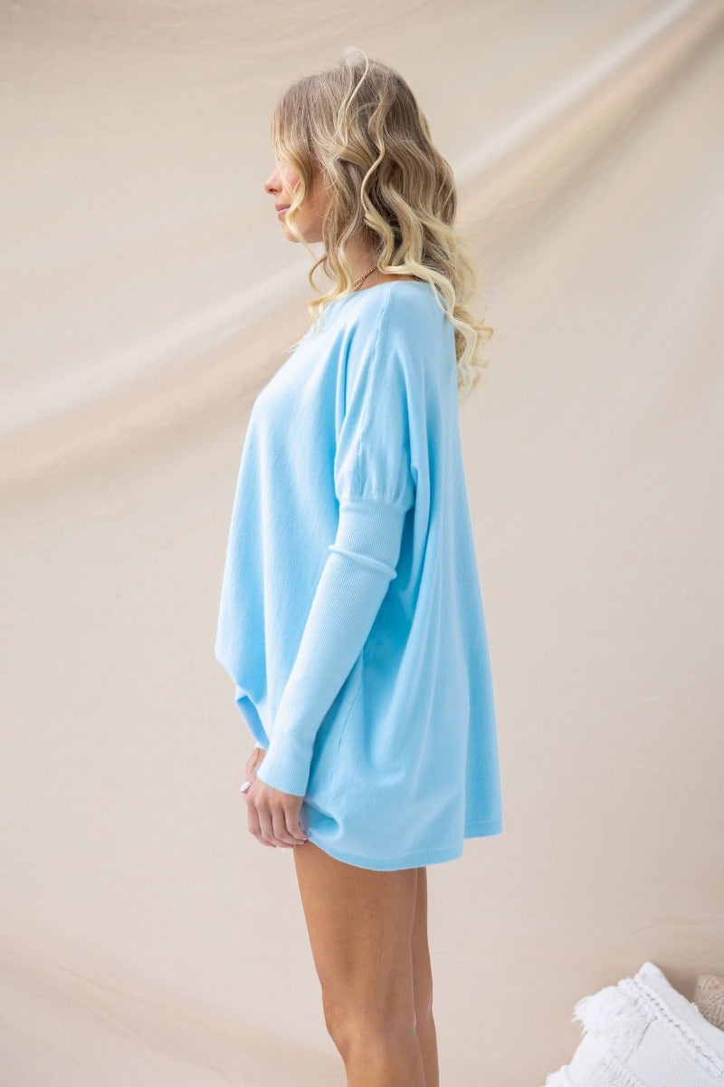 Light blue oversized knit top/dress with full-length sleeves, styled for a cozy look, made of 100% cotton.