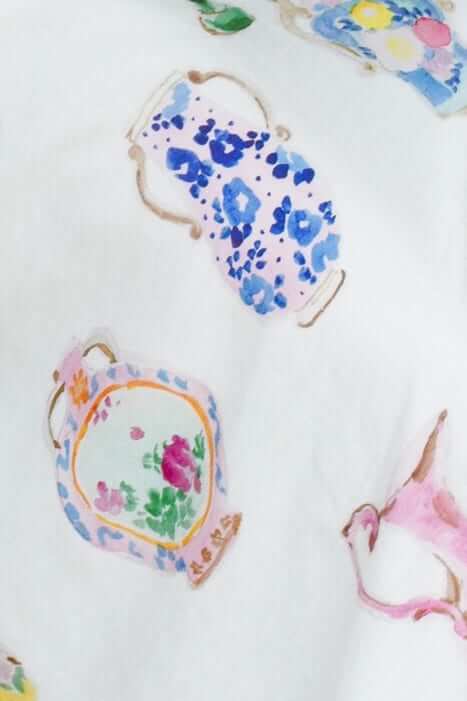 Soft white fabric featuring a colorful teapot pattern in pastel shades of blue, pink, and green.