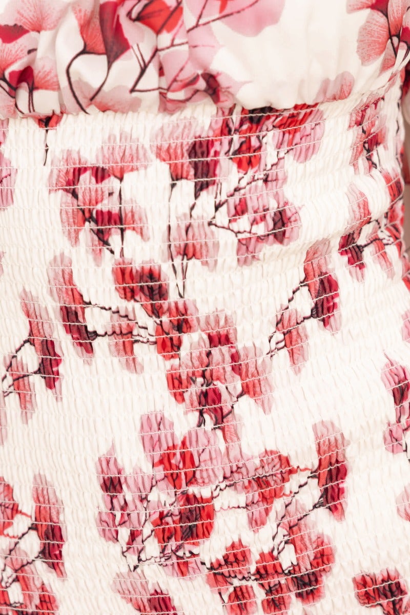 Close-up of floral patterns and textured fabric of the Gwenna Midi Dress, featuring shades of pink and red.