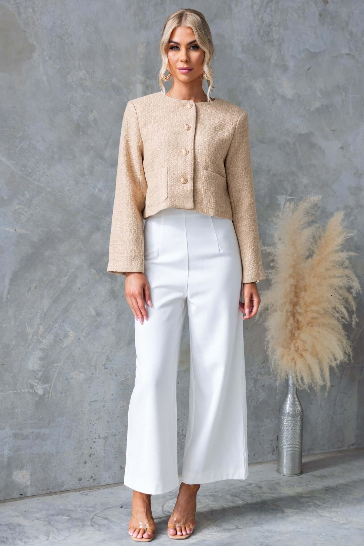 Model wearing Edam Pants with mid-high waist fit, styled with a beige button-up top against a textured background.