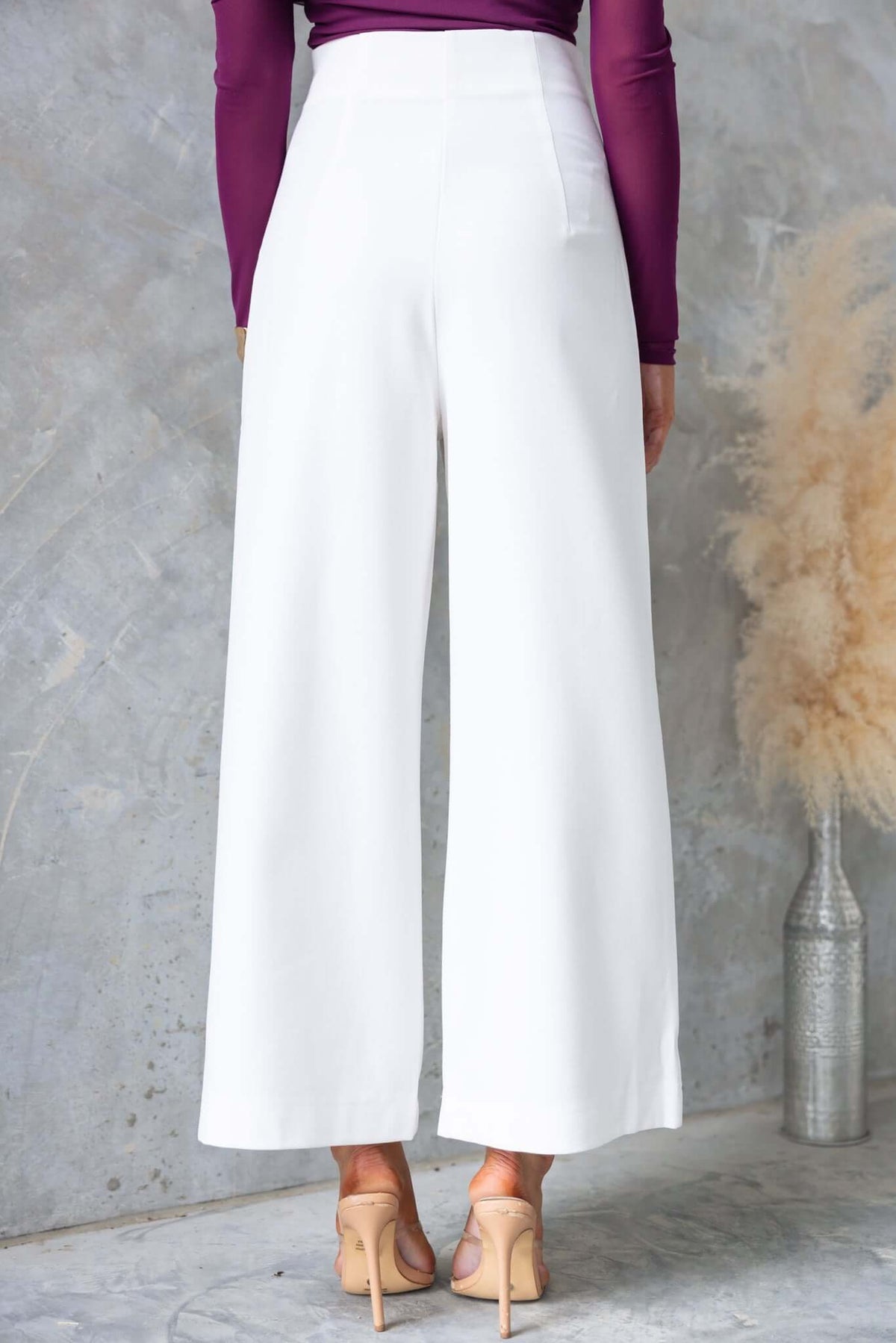 White Edam pants with mid-high waist, invisible side zip, and relaxed fit, styled with a purple top.