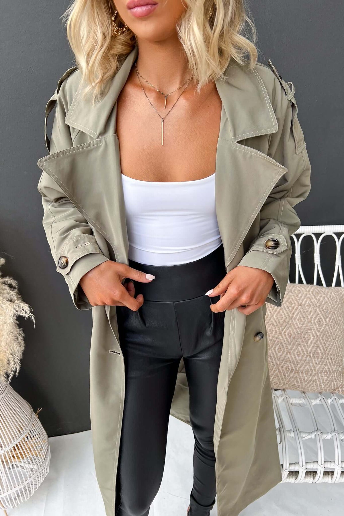 Eino Coat in olive green, featuring a trench design, collar, button closure, and removable belt, styled with black leggings.