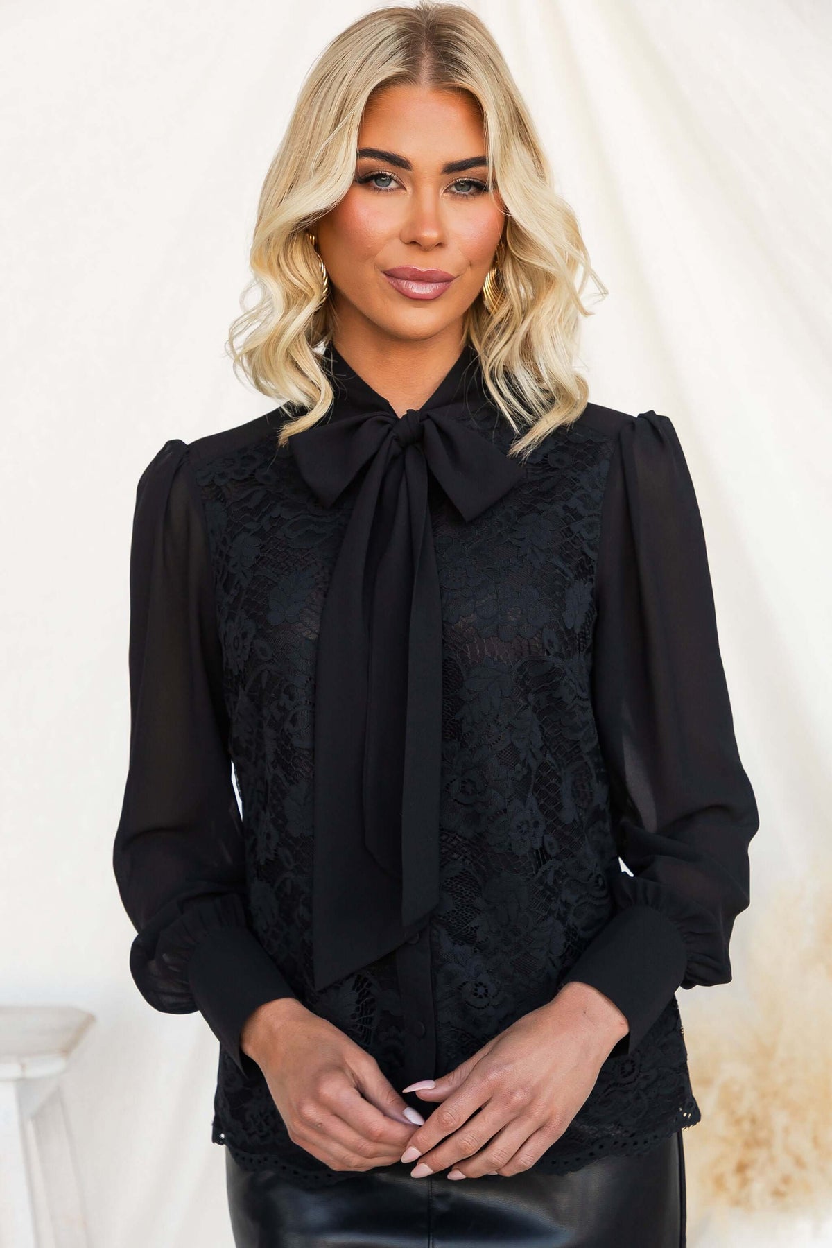 Elijah Shirt featuring a black lace design, tie neckline, and chiffon sleeves, styled elegantly.