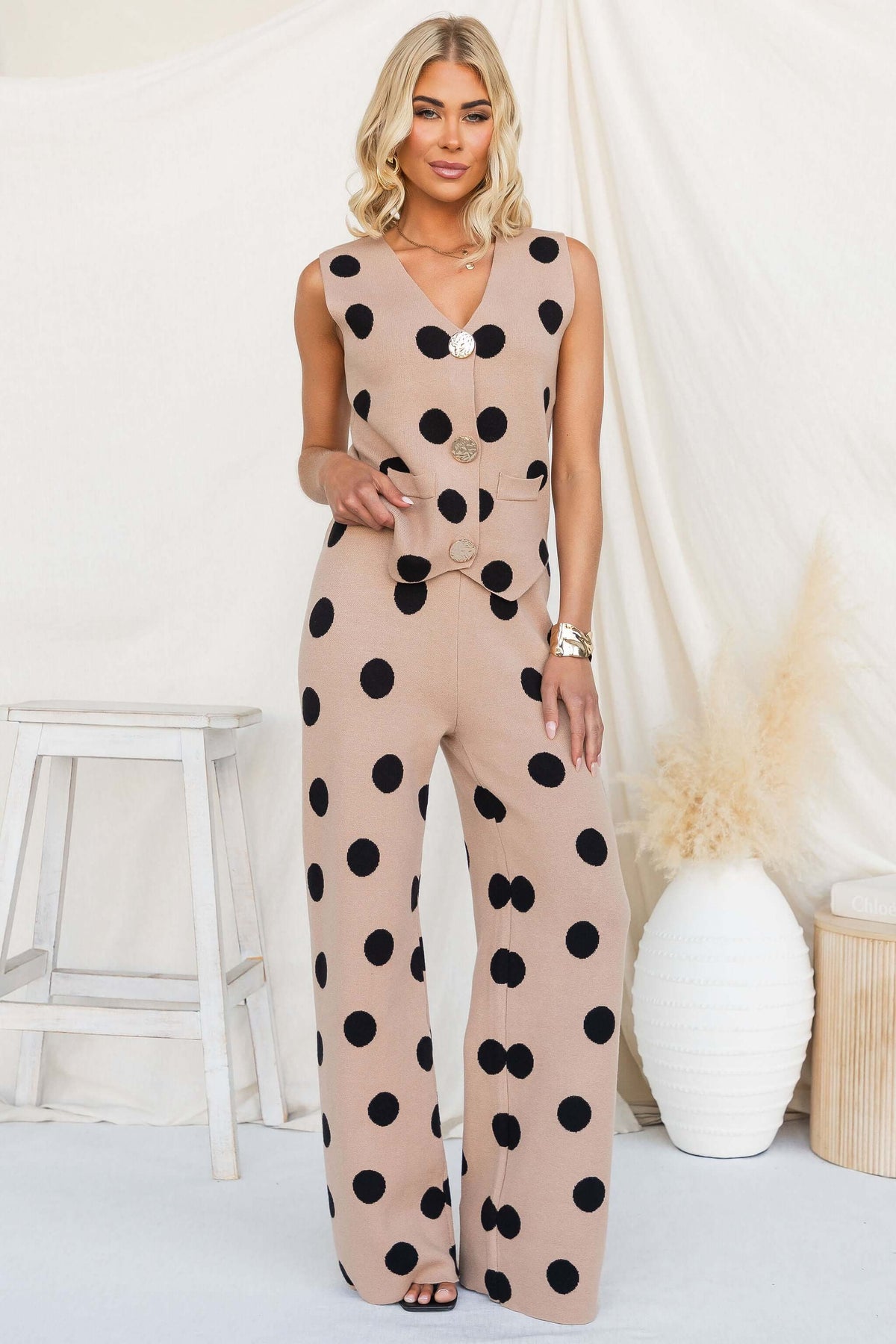 Elise Set featuring a knit material jumpsuit with black polka dots and a V-neckline, styled by a model.