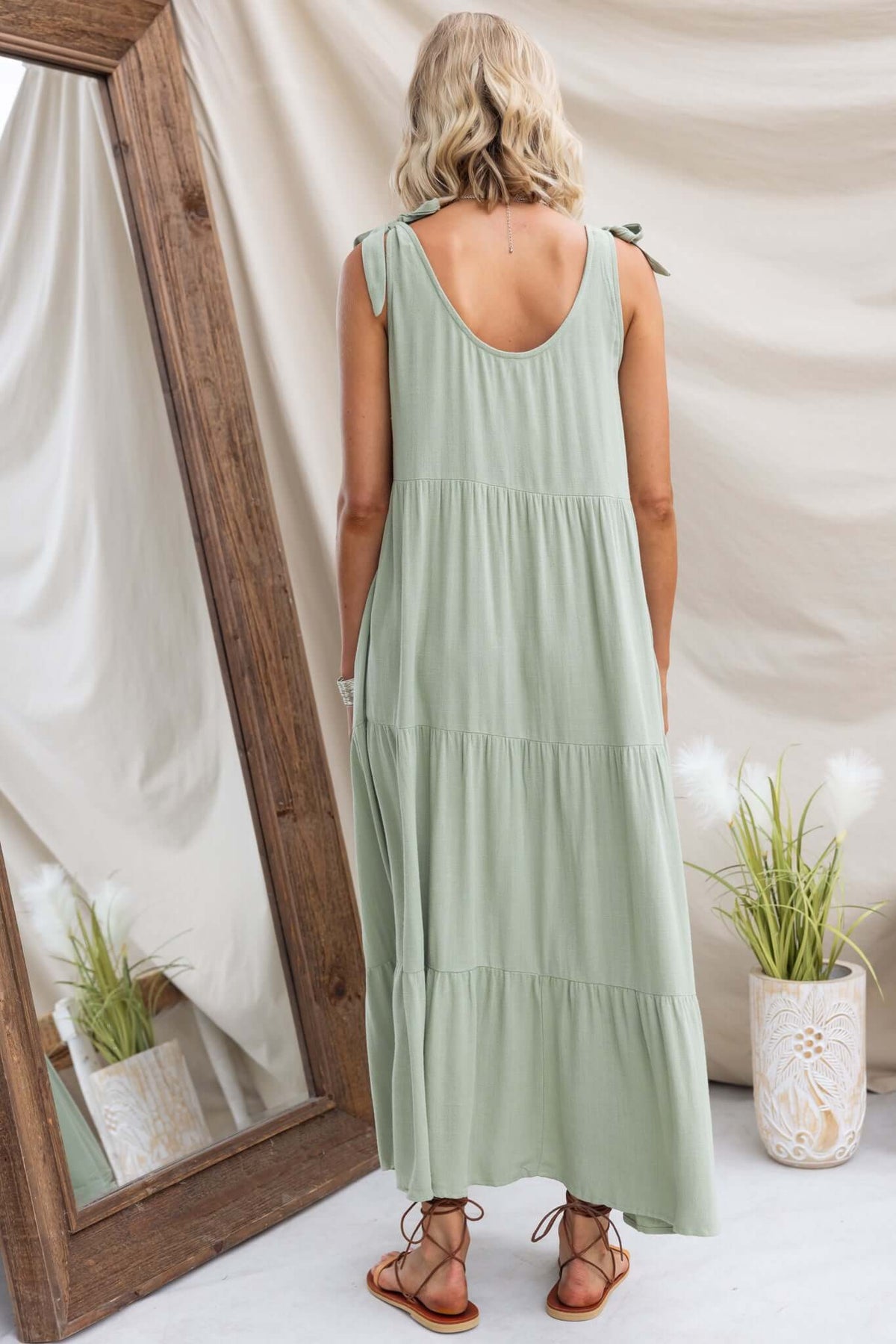Back view of Erikson Maxi Dress in soft green, featuring tie straps, tiered design, and pockets, perfect for relaxed summer wear.
