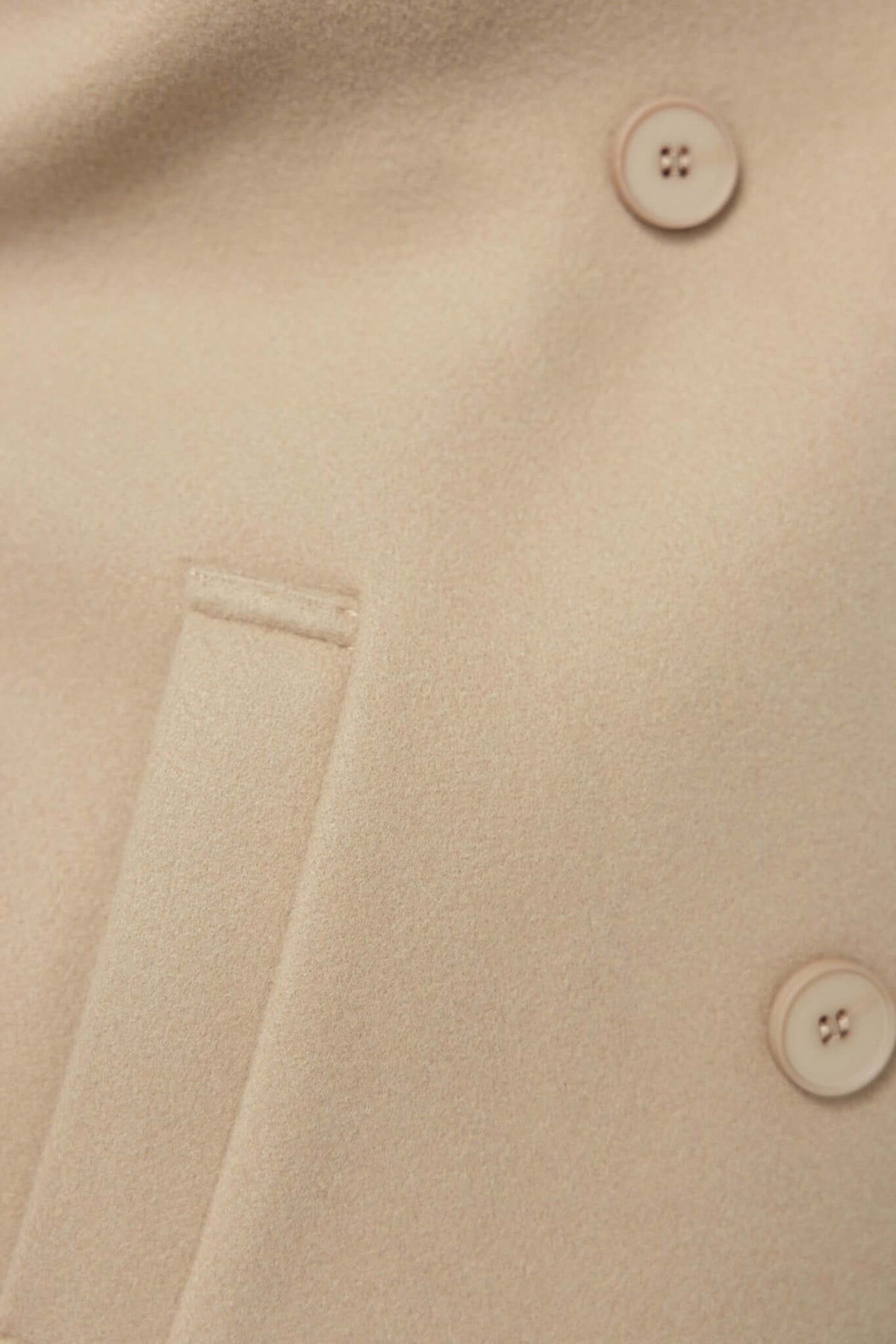 Close-up of Farina Coat showing soft fabric, buttons, and pocket detail in a warm beige color.