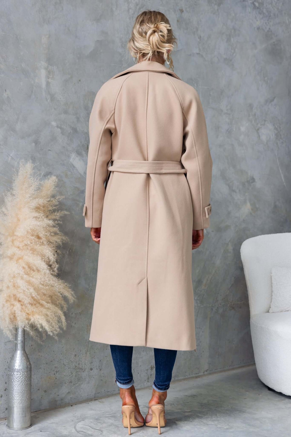 Model wearing a chic Farina coat, showcasing the longline fit and removable fabric tie from the back.