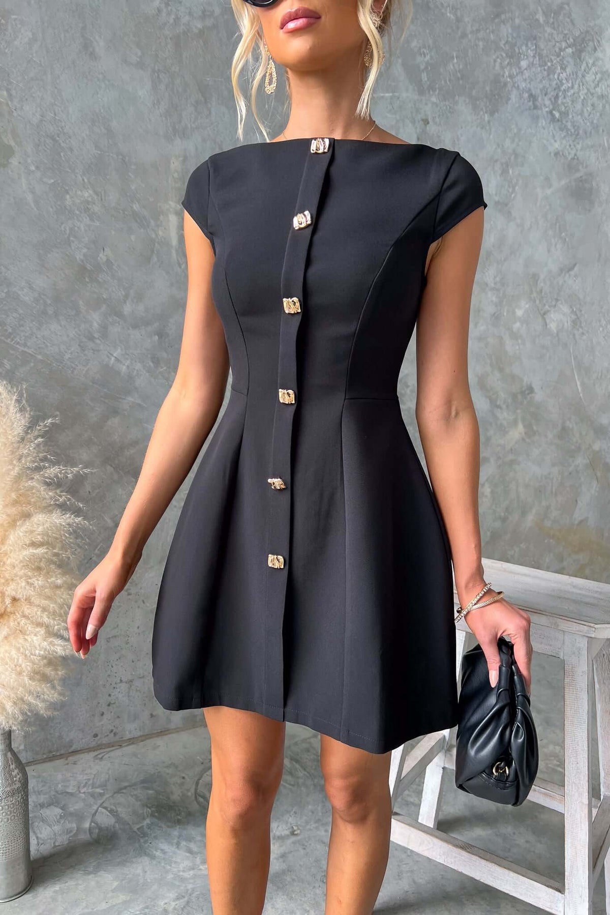 Feist Dress featuring a boat neckline, faux buttons, and flared skirt, styled by a model in a chic setting.