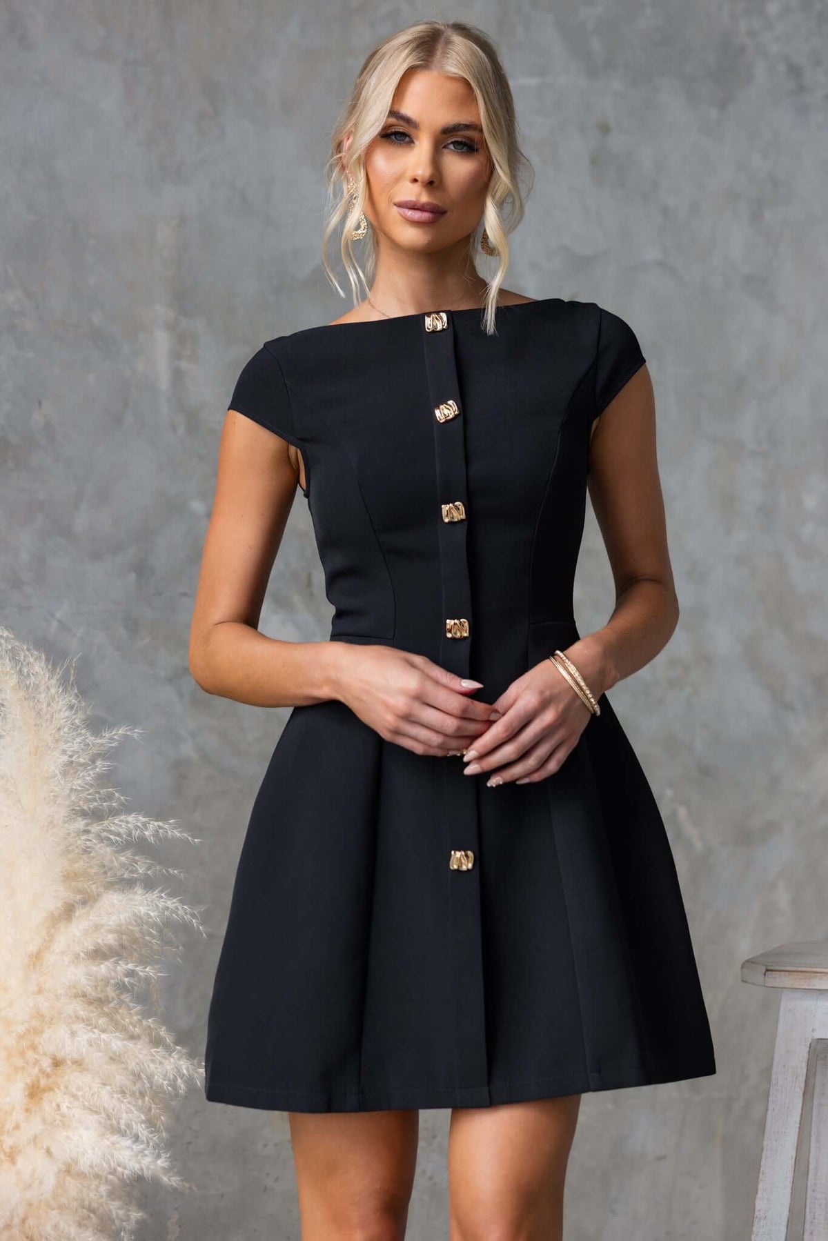 Model wearing the Feist Dress featuring a boat neckline and faux buttons, styled elegantly in a chic black color.