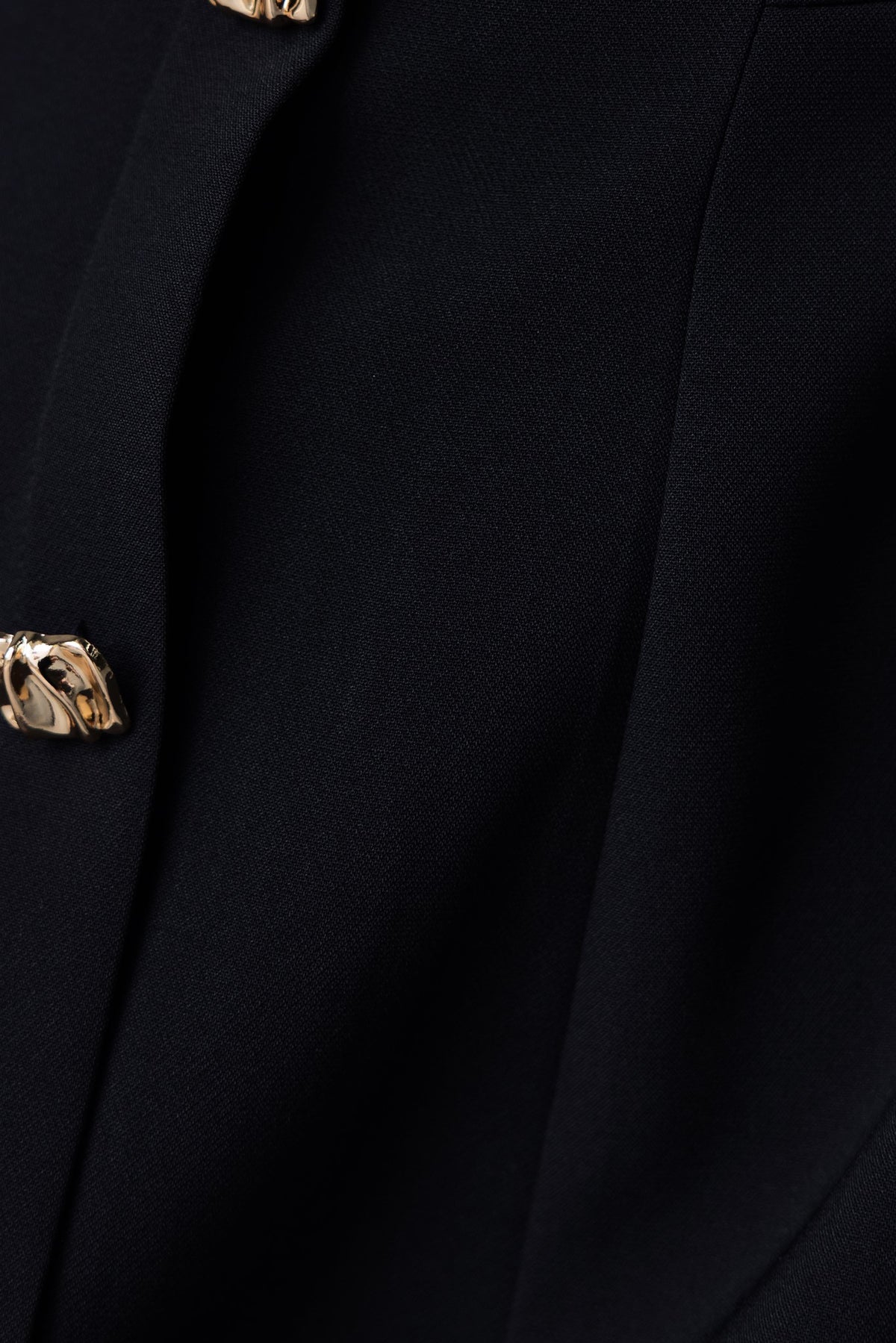 Close-up of Feist Dress showing boat neckline and faux buttons on a black fabric.