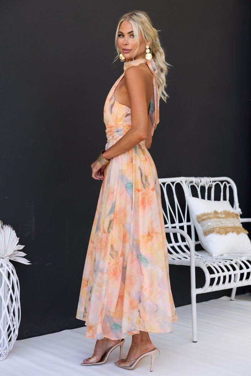 Model wearing Little Things Maxi Dress with floral print and high tie neckline, styled with accessories.