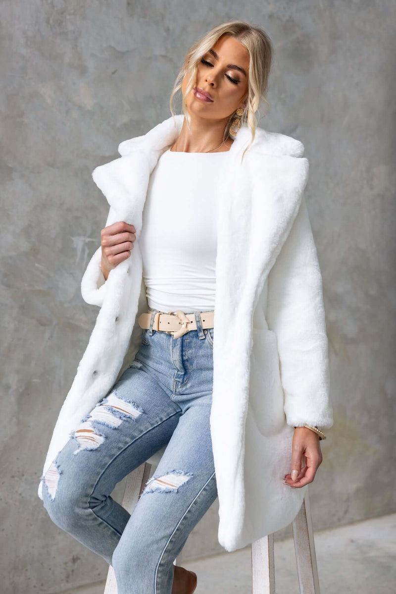 Model wearing a fluffy white frosted coat over a fitted top and distressed jeans, showcasing its stylish oversized fit.
