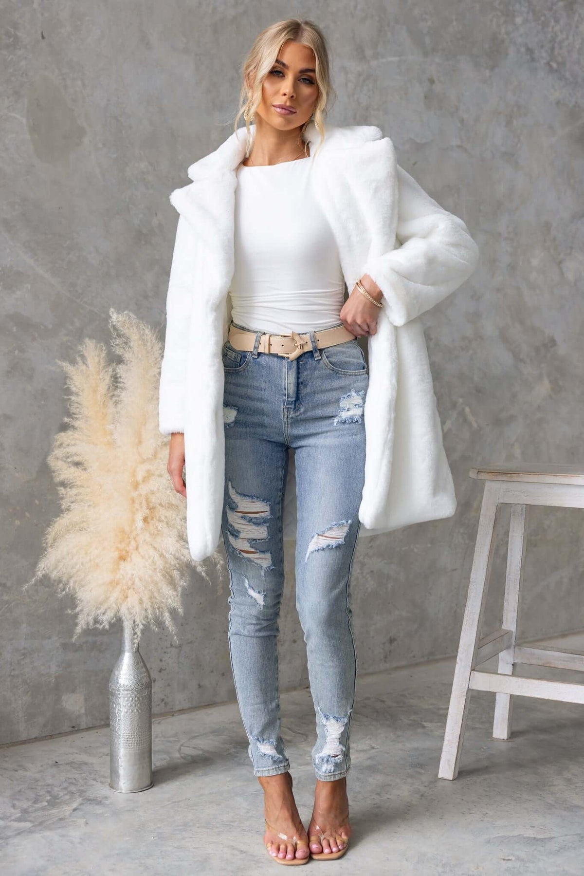 Model wearing a fluffy frosted coat over a white top and ripped jeans, showcasing a stylish oversized fit.