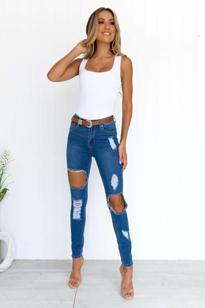 Model wearing distressed Glory Jeans with pockets, showcasing stretch denim and trendy rip details.