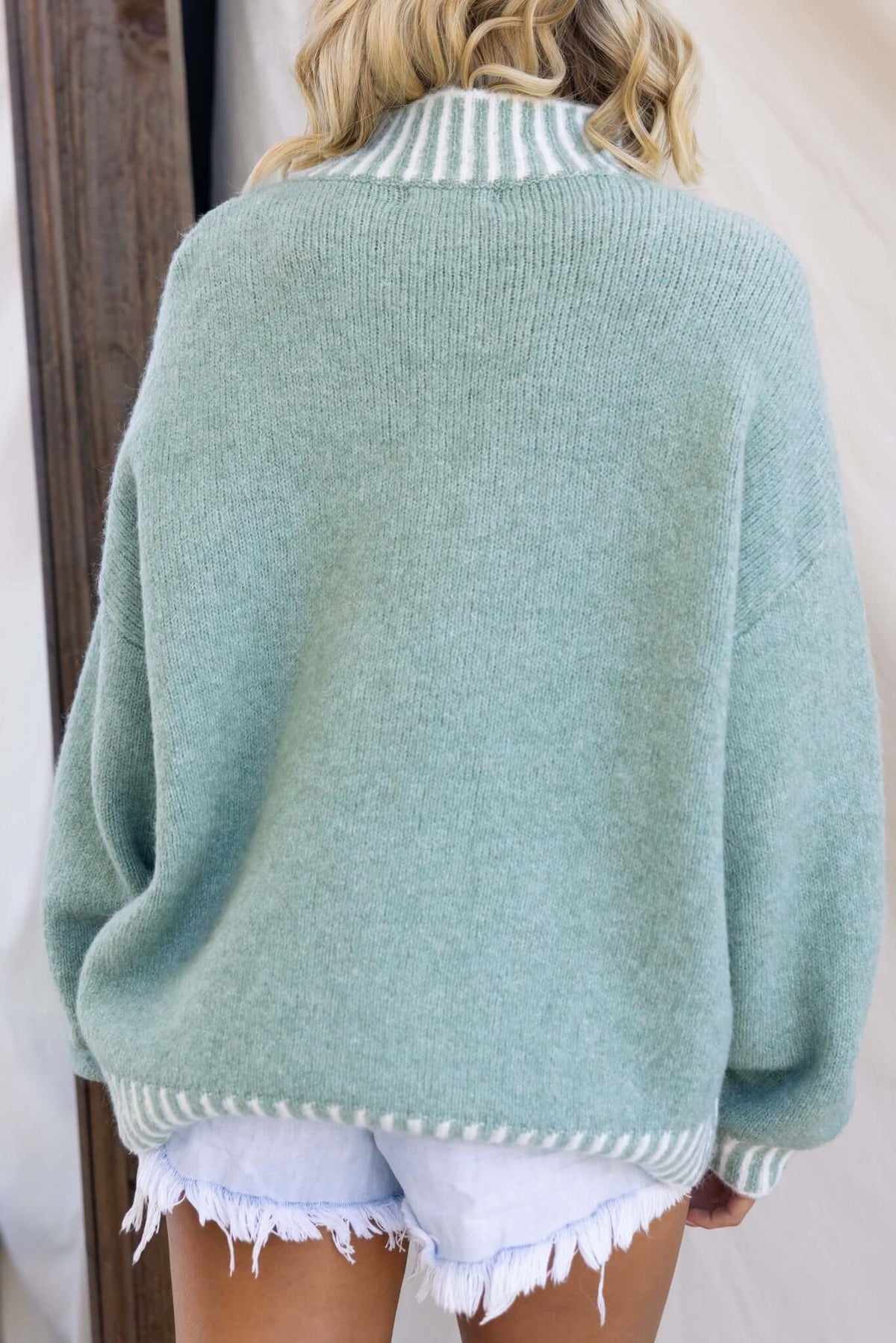 Back view of the Giorgio Jumper in mint green, featuring a high neckline and relaxed fit, styled with denim shorts.