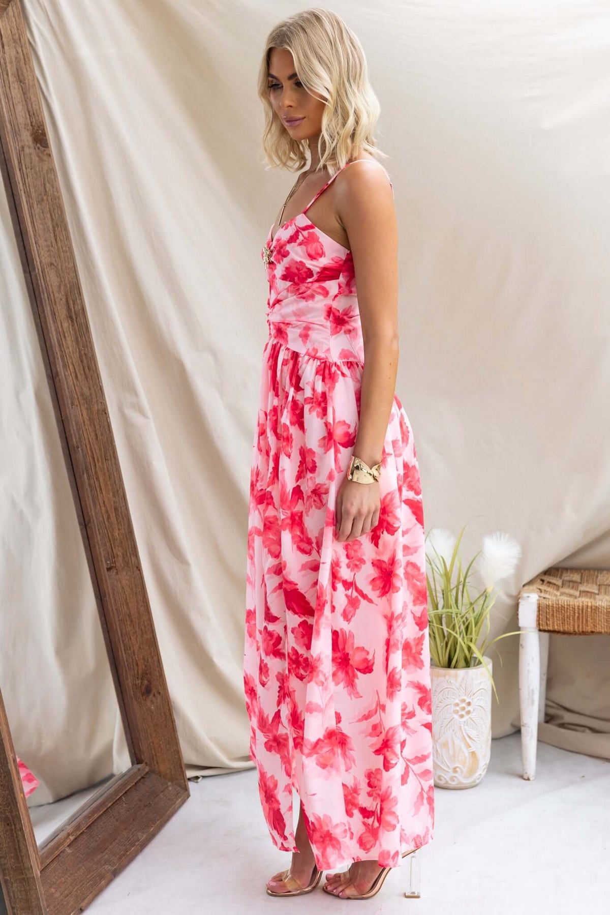 Model wearing the Hazelle Maxi Dress with floral print, adjustable straps, and gold hardware detail.