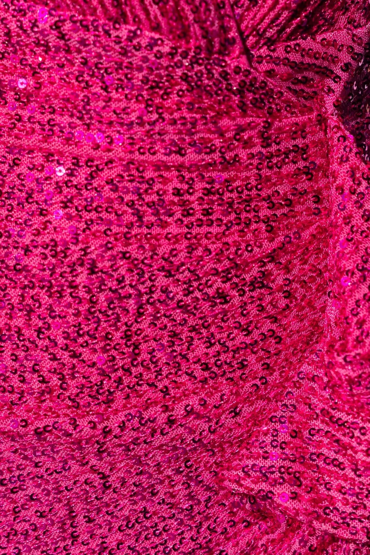 Close-up of sequins on a vibrant pink dress, showcasing its shimmering texture and luxurious detailing.