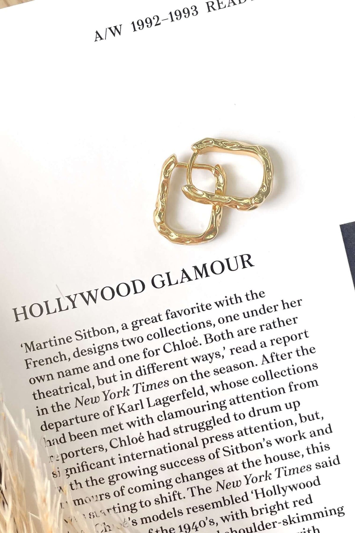 Gold Laila Earrings displayed on a fashion magazine with text about Hollywood glamour, showcasing their elegant design.