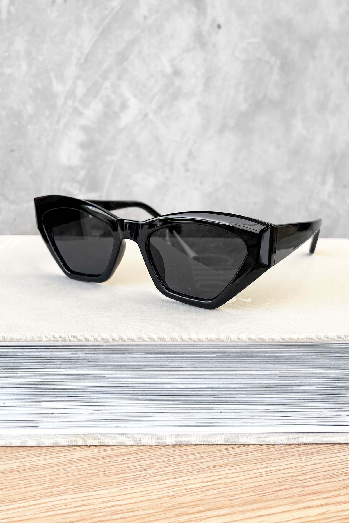 Stylish black cat-eye sunglasses displayed on a neutral background, perfect for trendy summer looks.