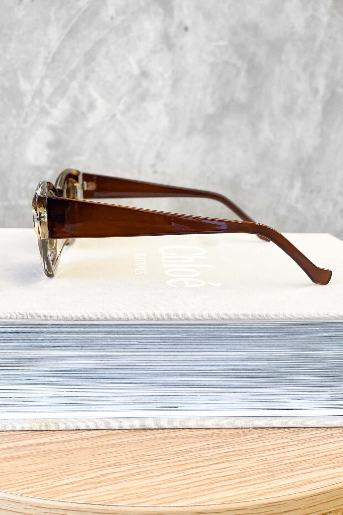 Side view of April sunglasses showcasing their stylish brown frames on a booklet background.