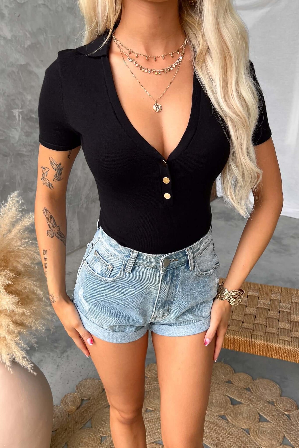 Black Denis Bodysuit with collar and button-up bust styled with distressed denim shorts.