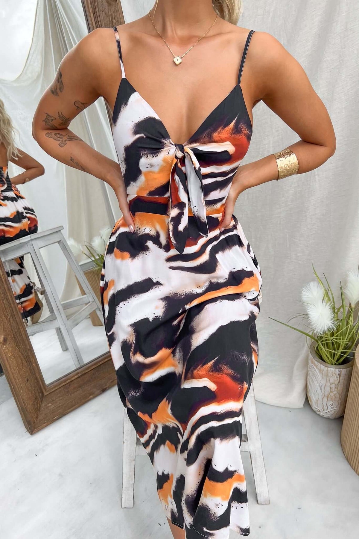 Model wears Cecilee Midi Dress with adjustable straps and tie at bust, featuring a vibrant abstract print.