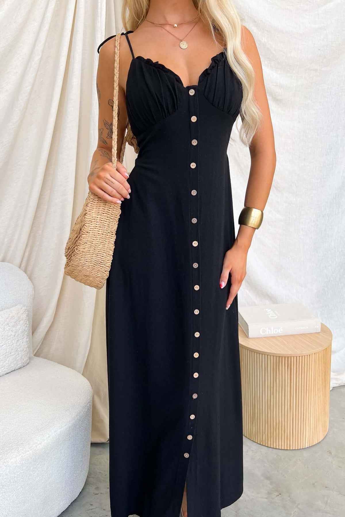 Woman wearing the Damico Maxi Dress, featuring tie straps, faux buttons, and a front split.