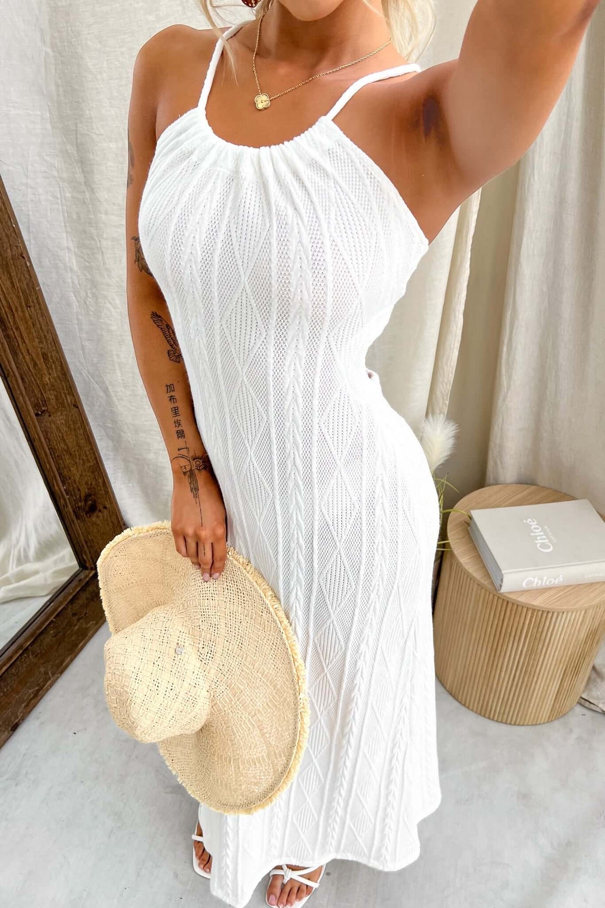 Model wearing Dream Weaver Maxi Dress in white, featuring a tie neckline and cut-out back, paired with a straw hat.
