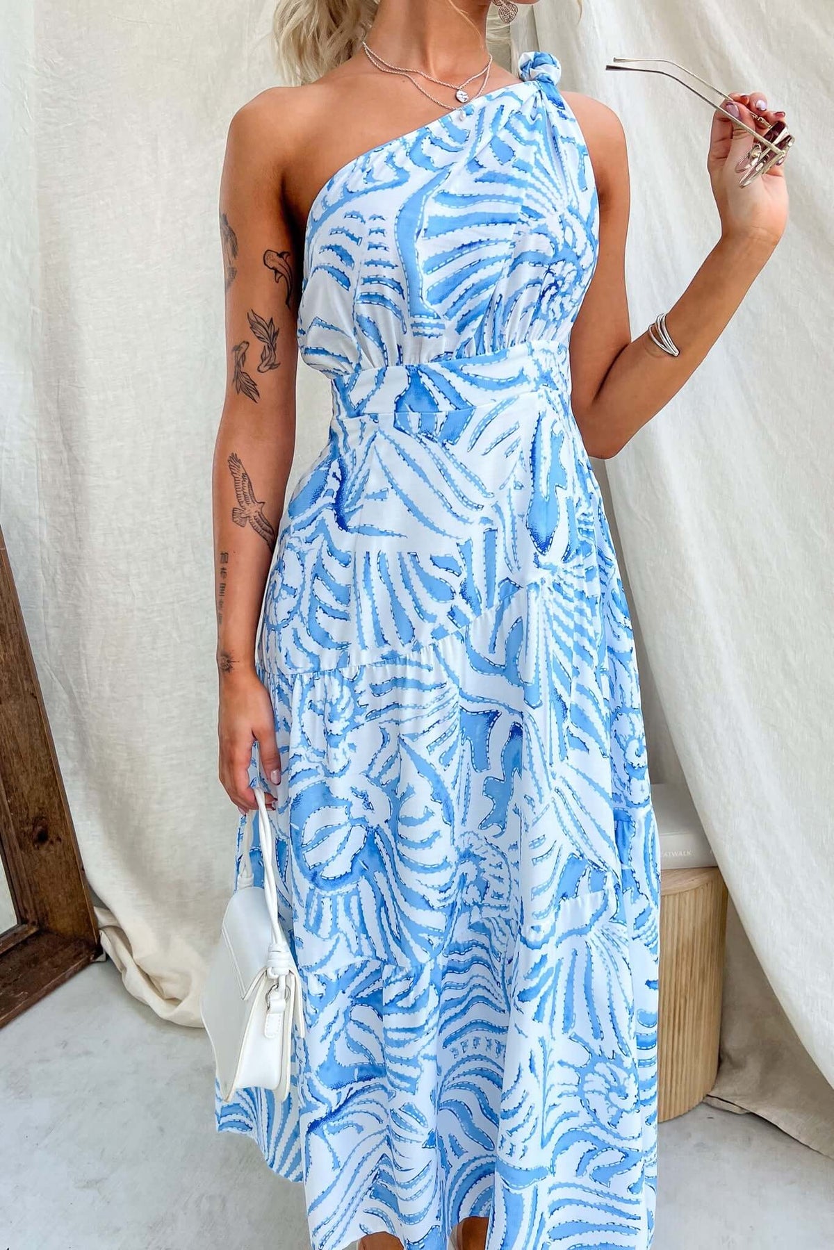 Model wearing the Qassidy Midi Dress, featuring a one-shoulder neckline and flowing design in blue and white pattern.