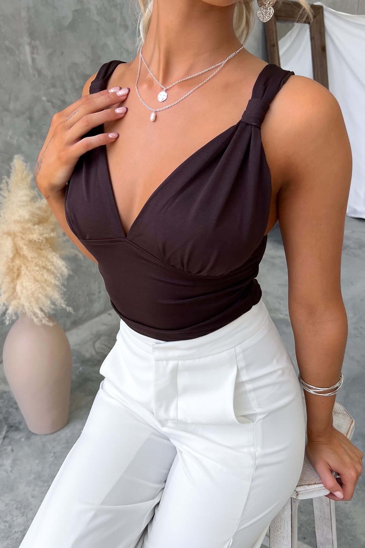 Elegant Kattan Top with V-neckline, featuring stretch material. Styled with white pants and layered necklaces.