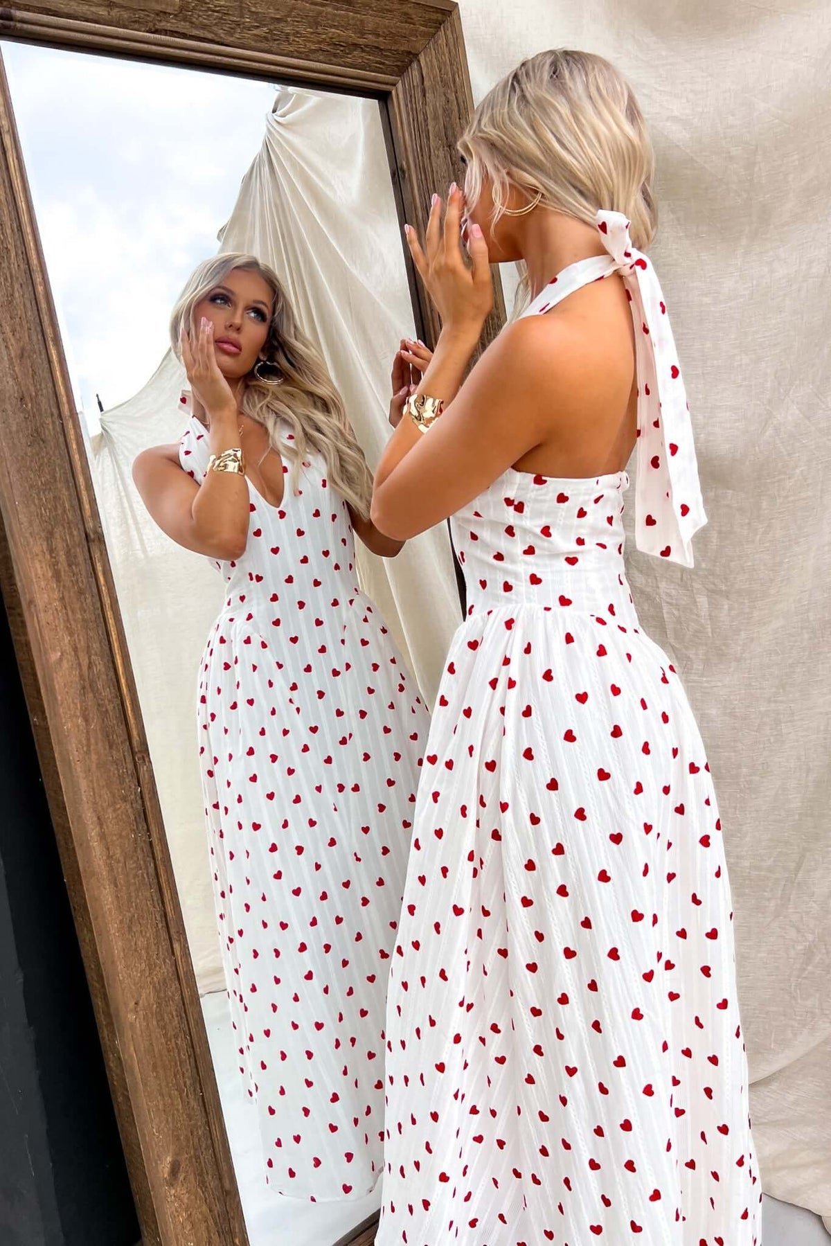 Model wearing Imarnie Maxi Dress with tie neckline, featuring heart print, looking in a mirror.