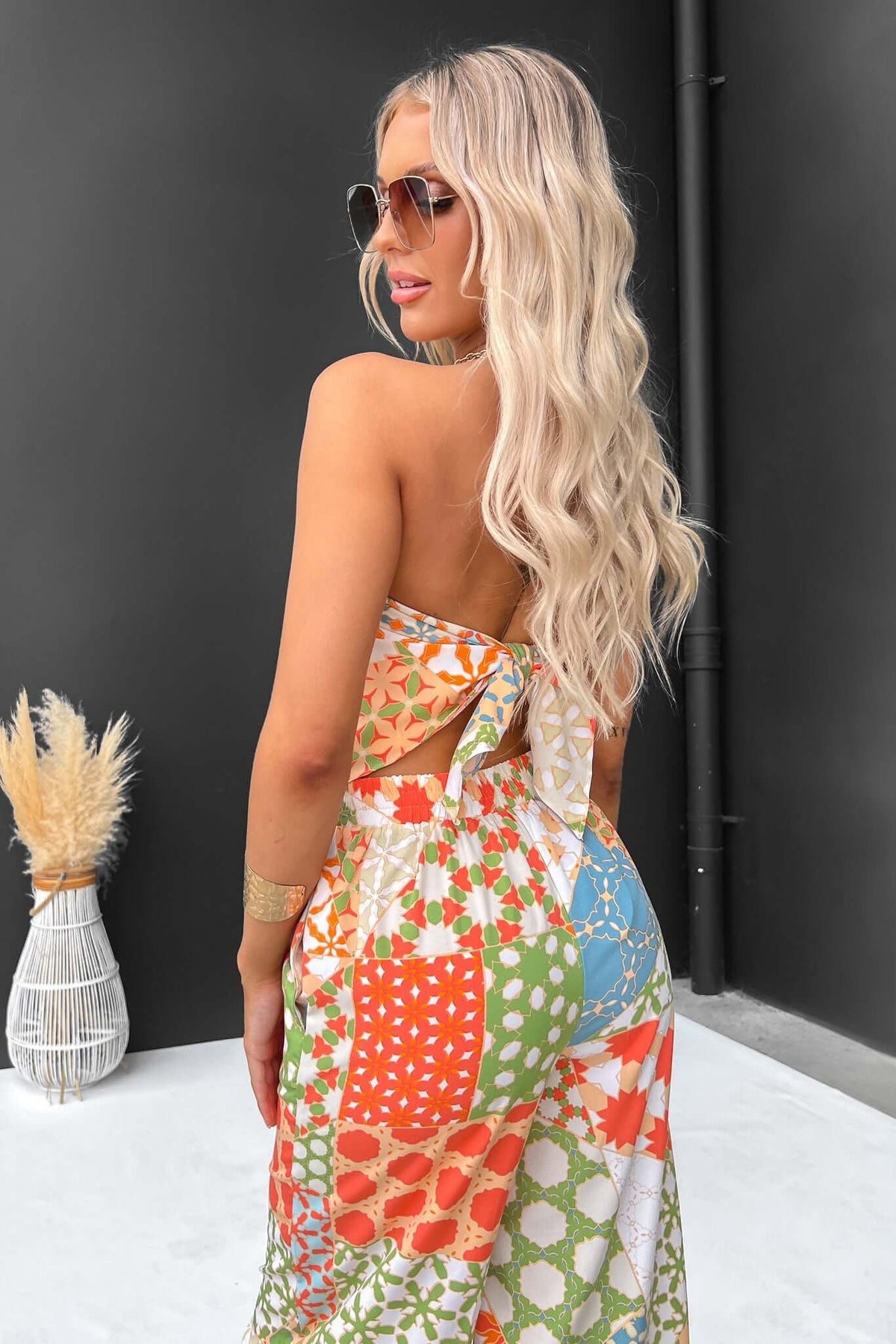 Woman wearing colorful Lorinda Top, showcasing its scarf tie design and vibrant patterns, perfect for summer styling.