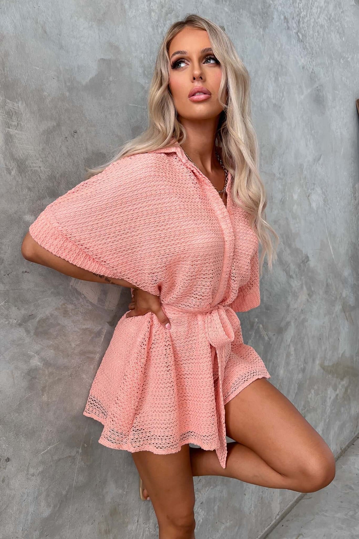 Joner Playsuit in soft pink, featuring a collar, button-up front, and removable tie, styled in a relaxed fit.