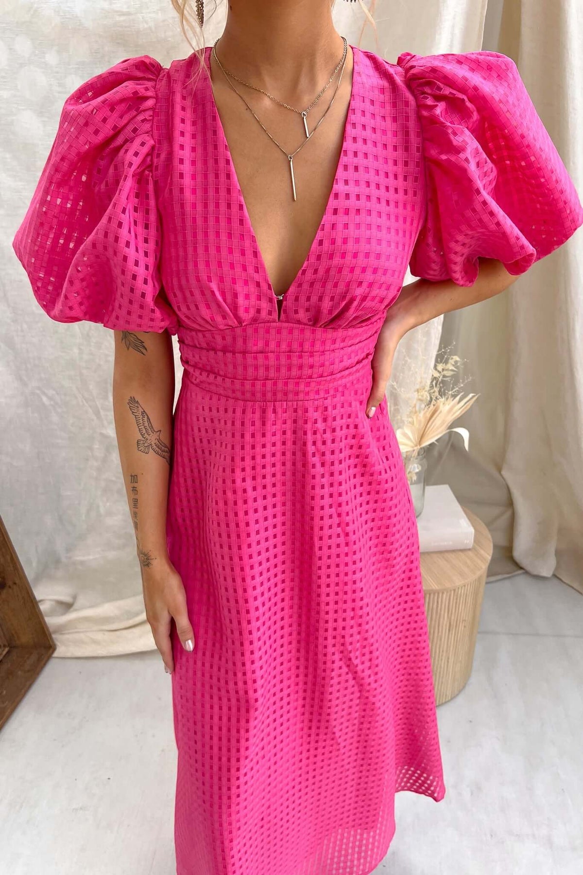 Nosita Midi Dress in vibrant pink with puff sleeves and a V-neckline, featuring textured fabric and pockets.
