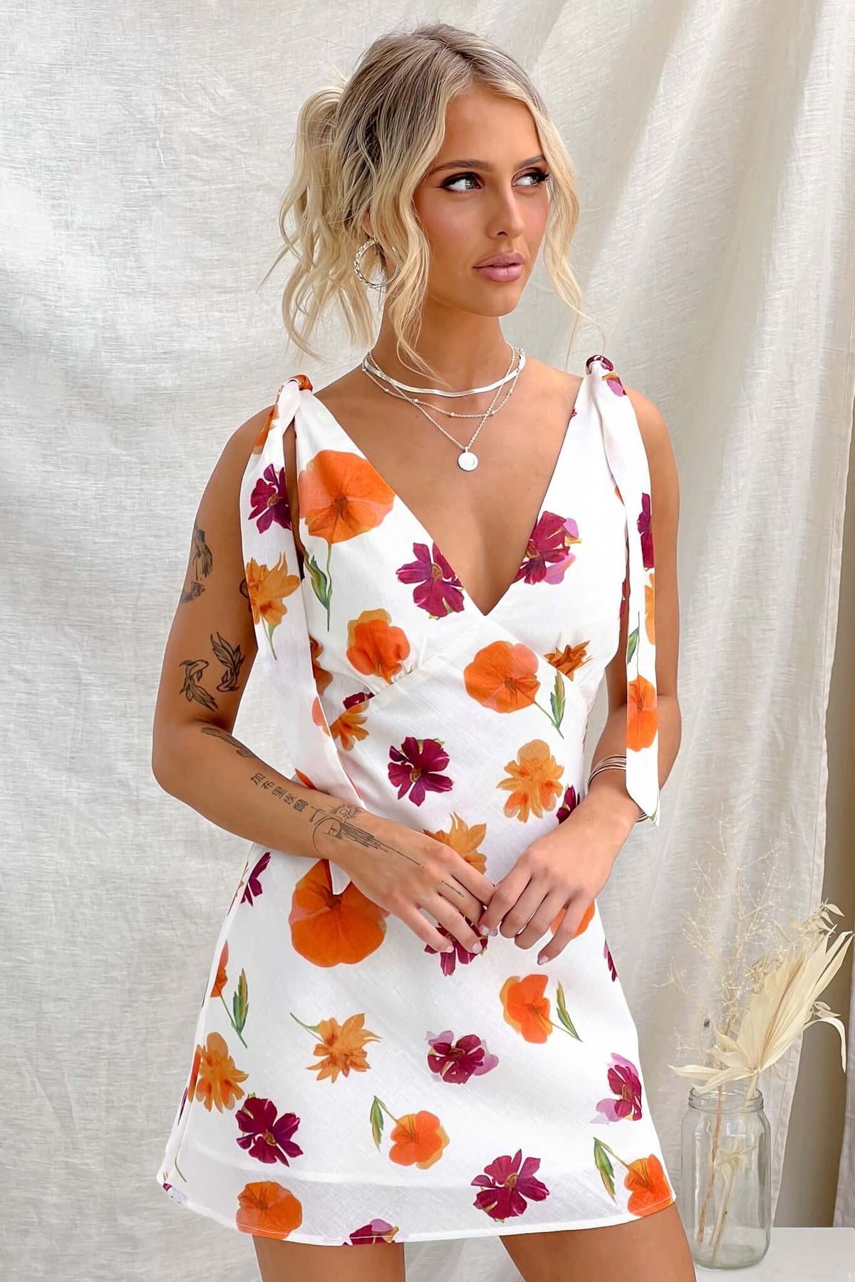 Kinsey Dress featuring floral print, adjustable tie straps, and a light cotton feel, modeled by a woman.