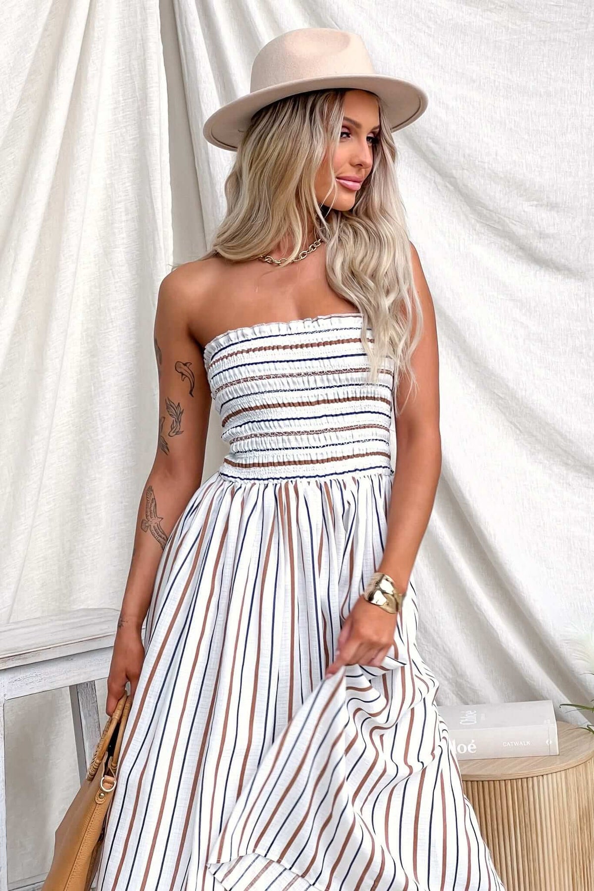 Elkie Midi Dress featuring a strapless design, elastic bodice, and striped pattern, worn by a model with a hat.