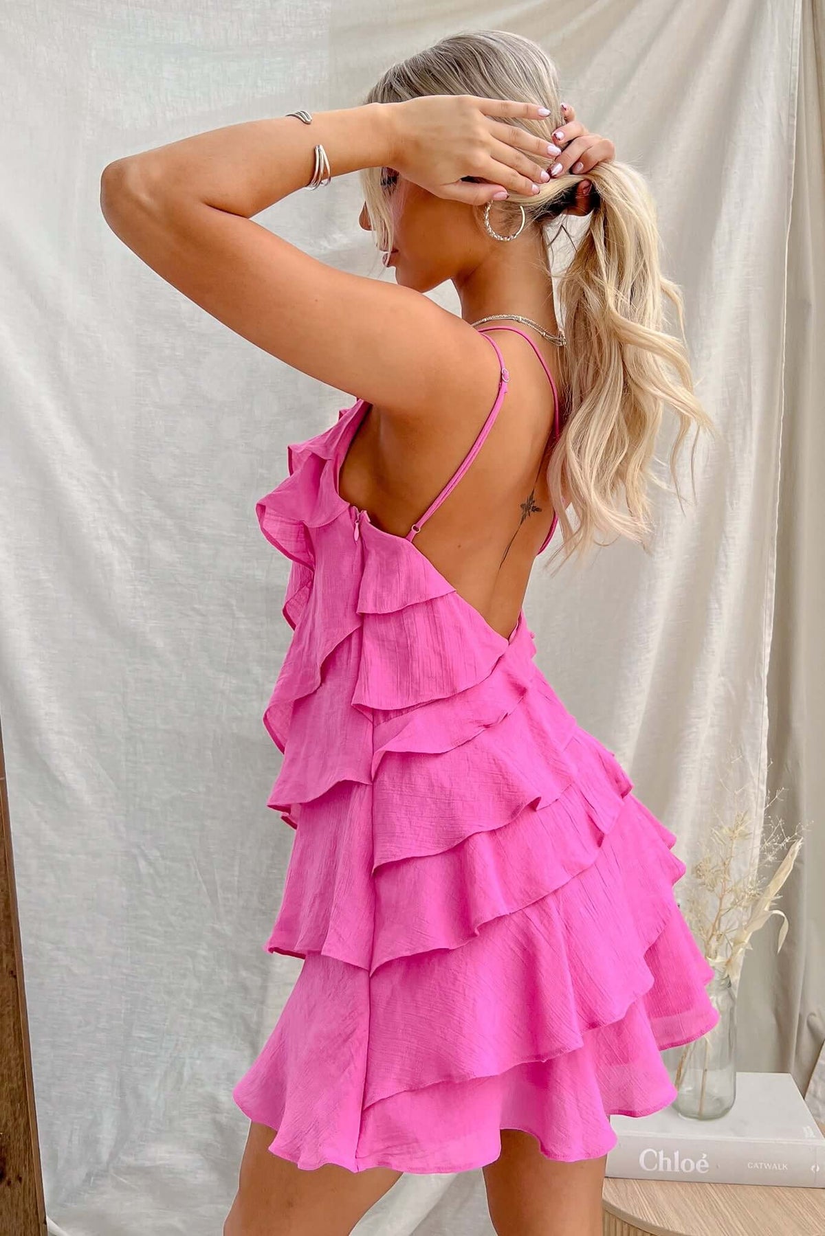 Stylish back view of a pink ruffled Lolita dress with adjustable straps and layered design.