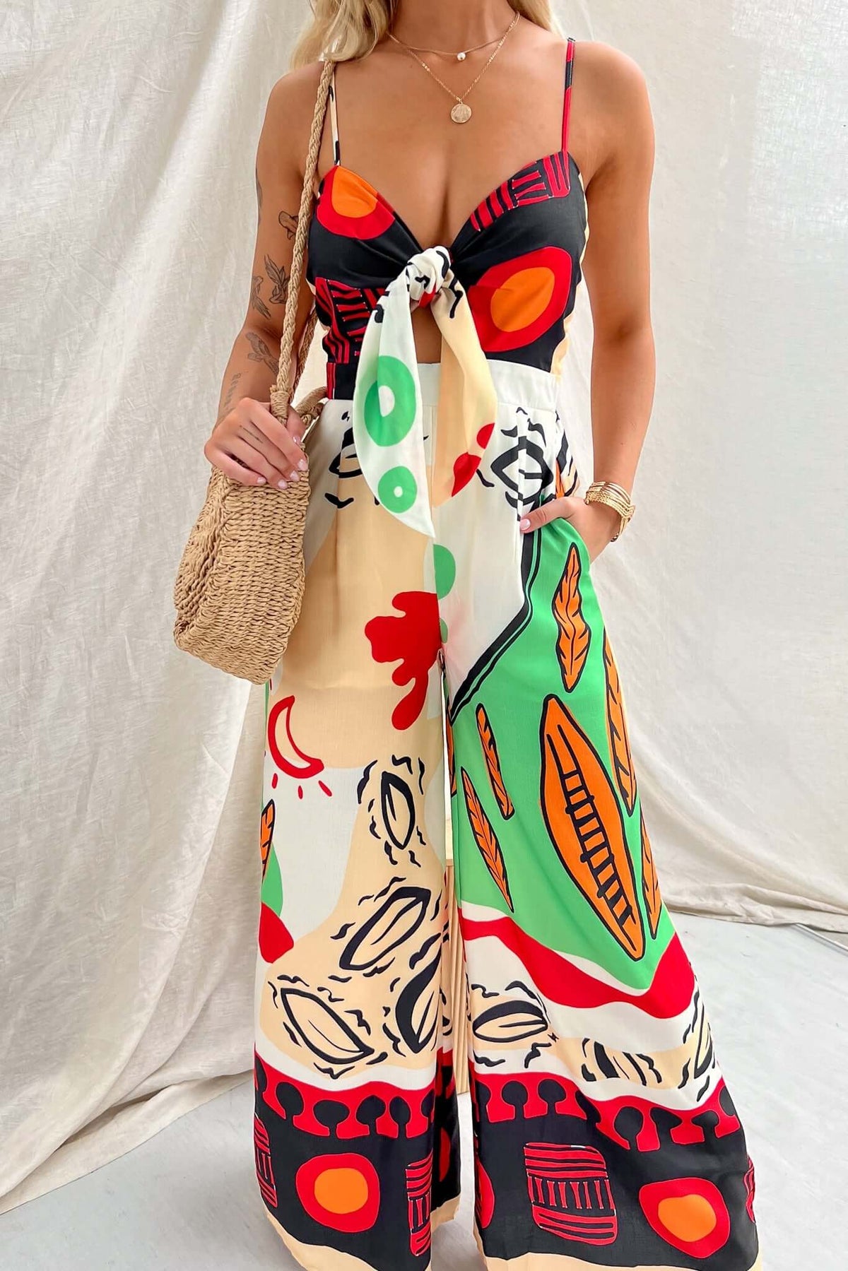 Model wearing Sun Dazed multi-colour print jumpsuit with adjustable straps and tie at bust.