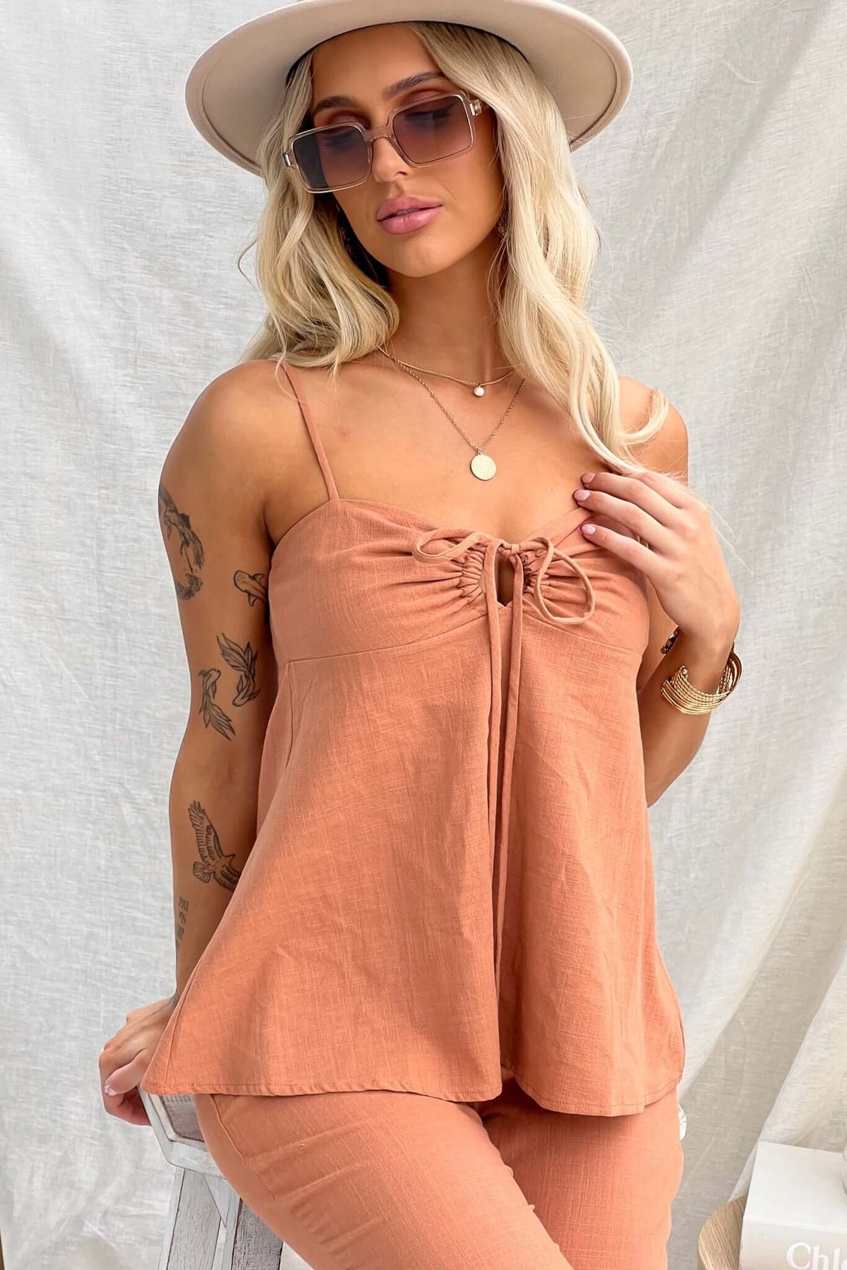 Model wearing the Stelline Top with adjustable straps and tie at bust in a soft peach color.