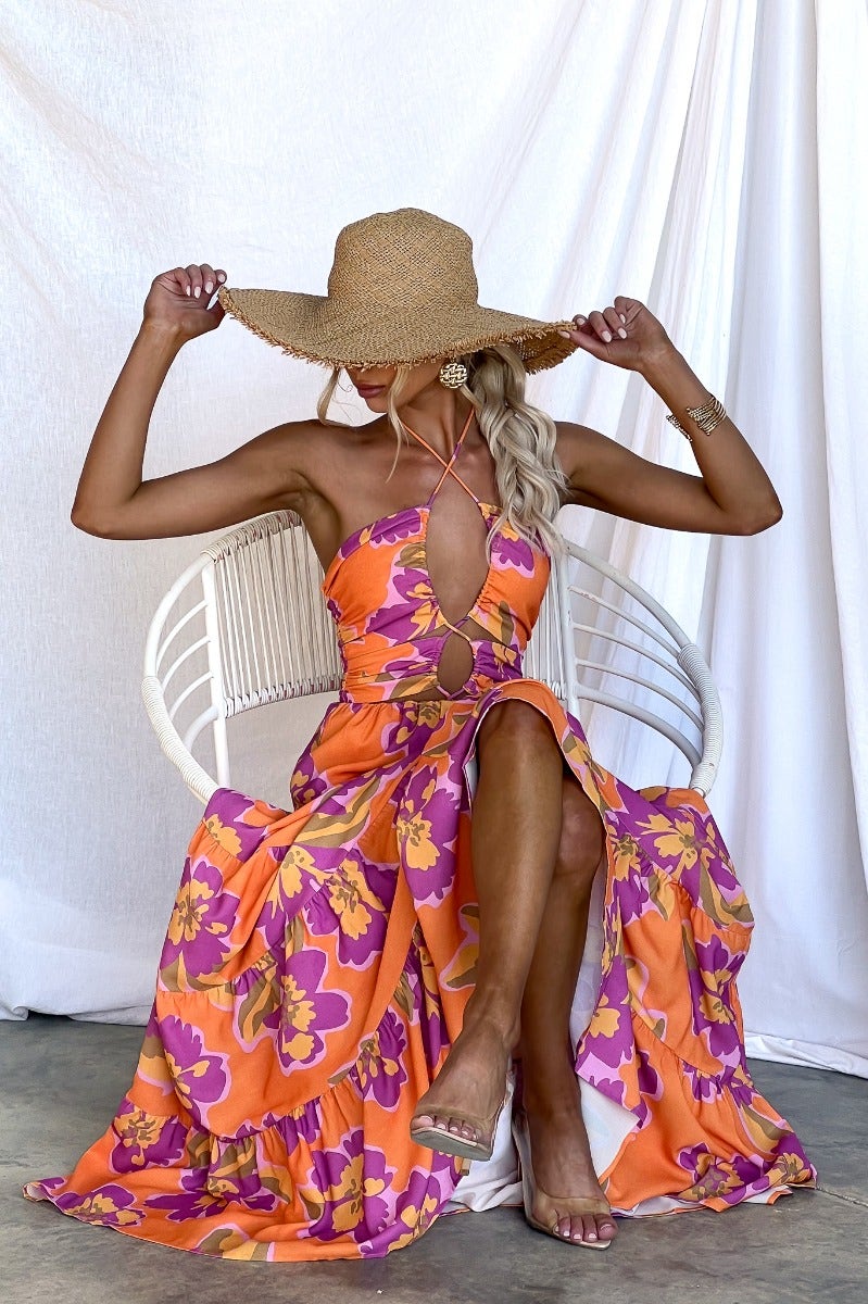 Model wearing the Over Joyed maxi dress with floral print, adjustable halter neckline, and cut-outs, styled with a large sun hat.