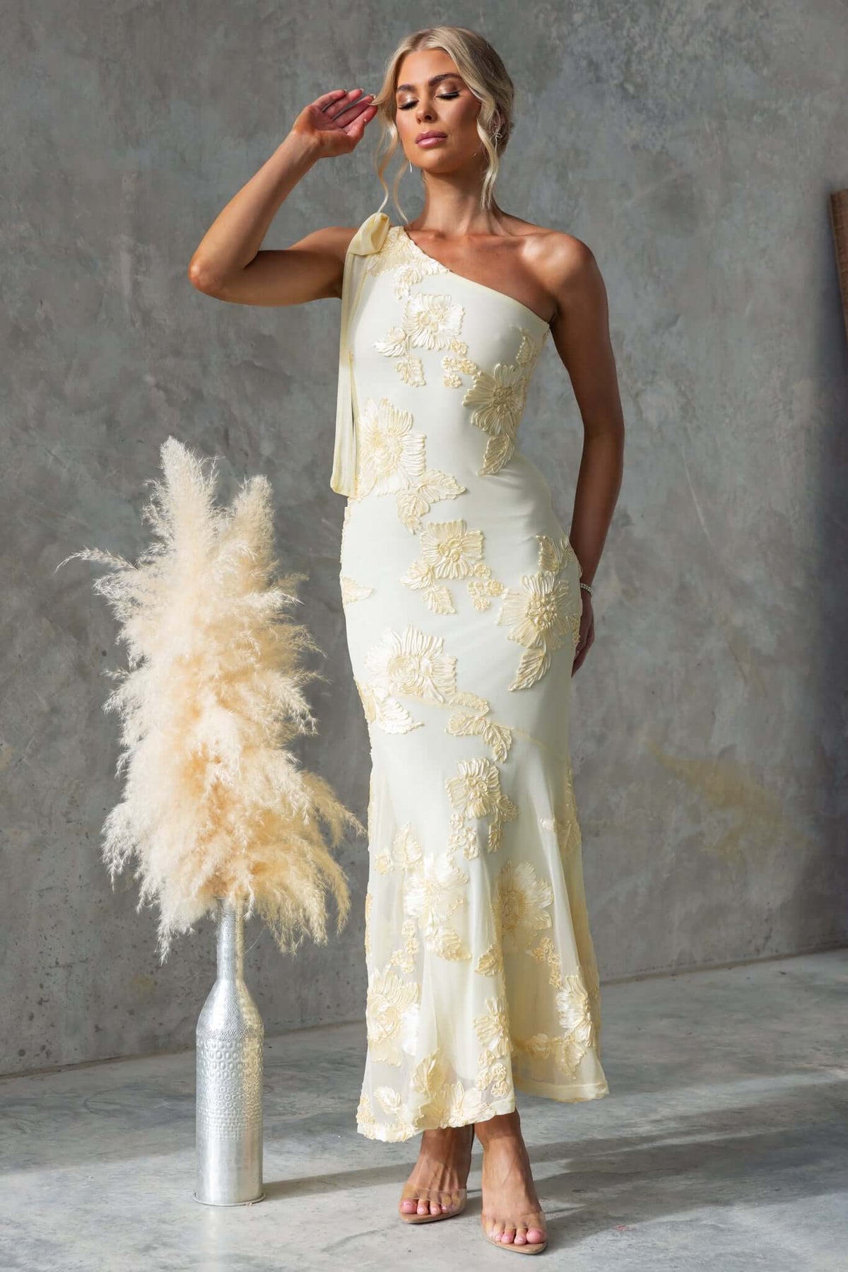 Inspire Maxi Dress featuring a one-shoulder neckline and embroidered material, styled with elegant accessories.