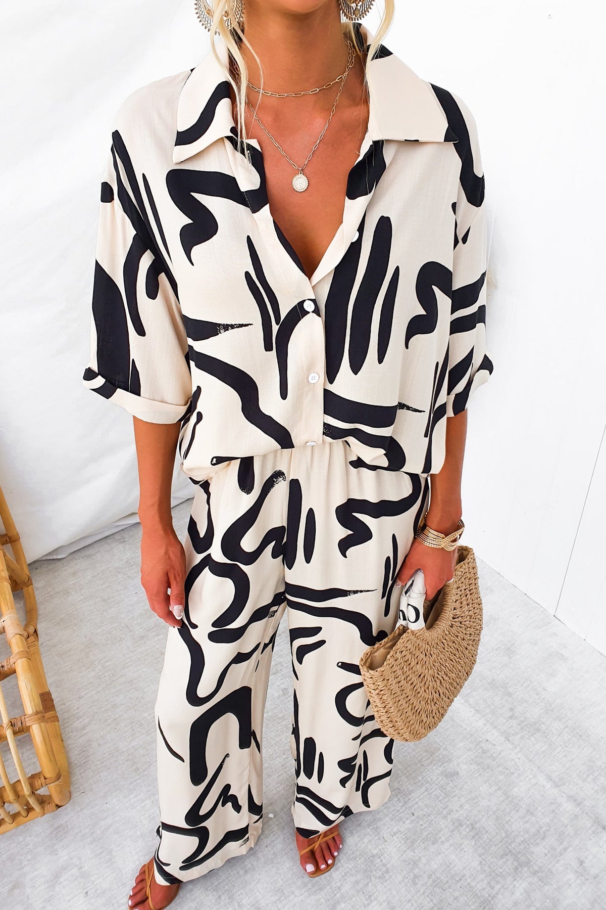 Model wearing Arwen Set with abstract print shirt and pants, featuring a button-up front and elastic waist.