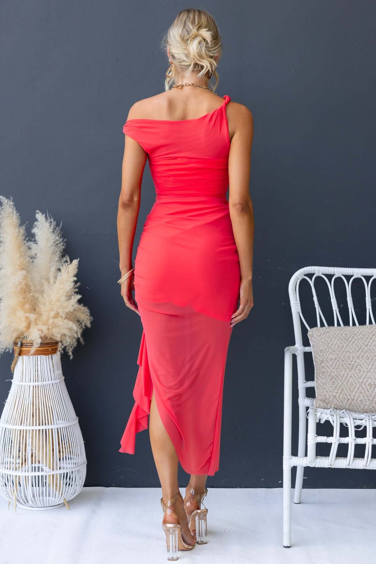 Model in a coral Iroha Maxi Dress showcasing twist straps and asymmetric hem, perfect for a stylish summer look.