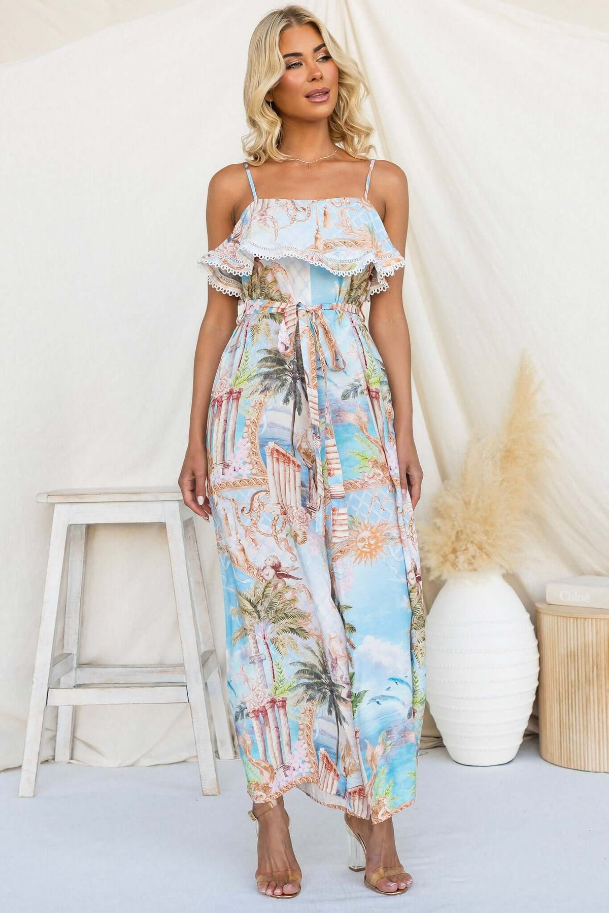 Model wearing Island Escape Jumpsuit with adjustable straps and floral print, showcasing tropical design.