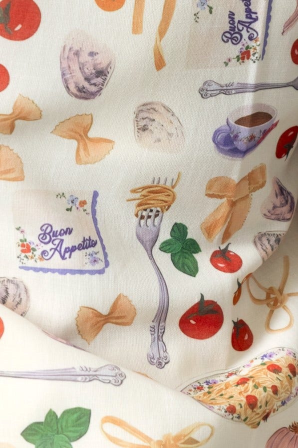 Vibrant fabric featuring pasta, tomatoes, and kitchen motifs with 'Buon Appetito' text in a whimsical design.