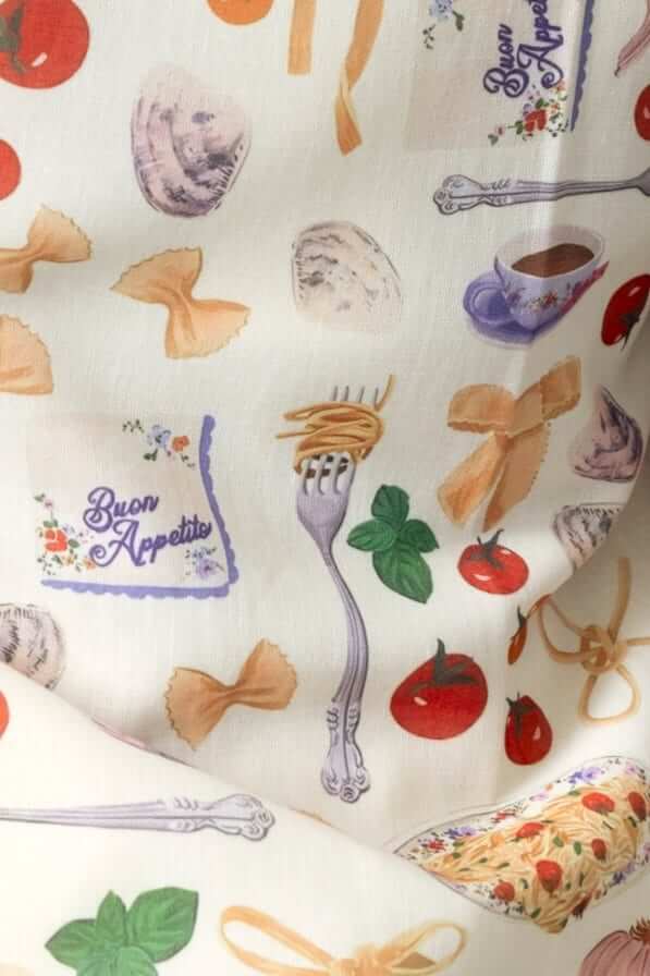 A playful fabric pattern featuring pasta, tomatoes, and kitchen utensils with 'Buon Appetito' text.