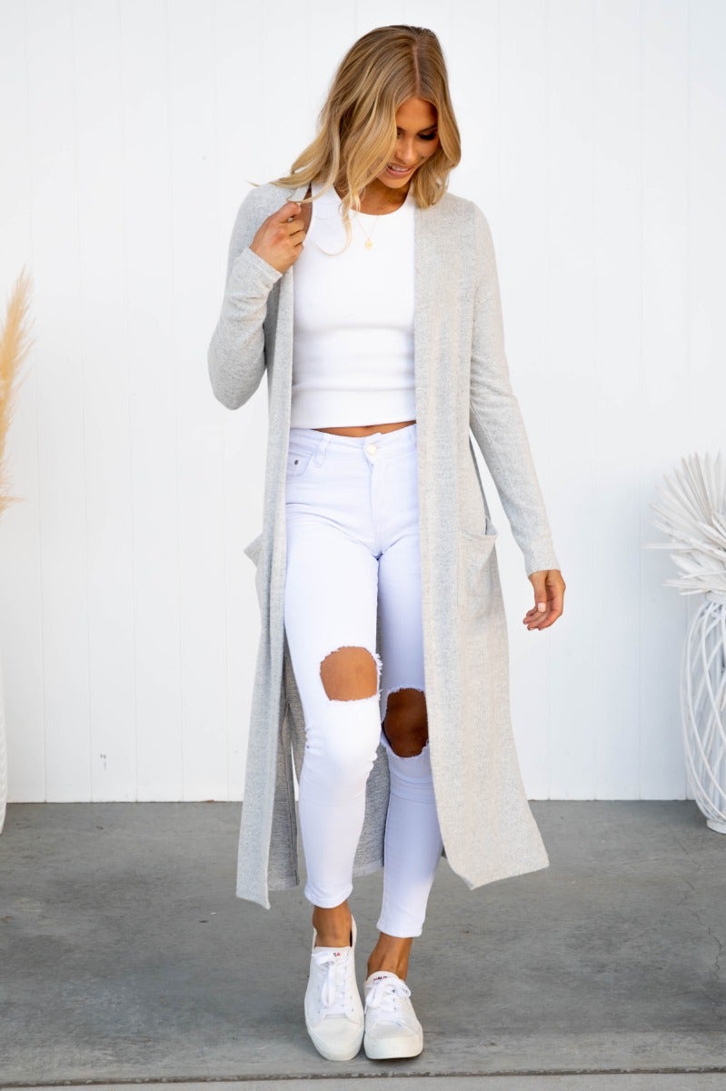 Izzy Cardigan in textured knit, featuring pockets and side splits, styled with white ripped jeans and a cropped top.