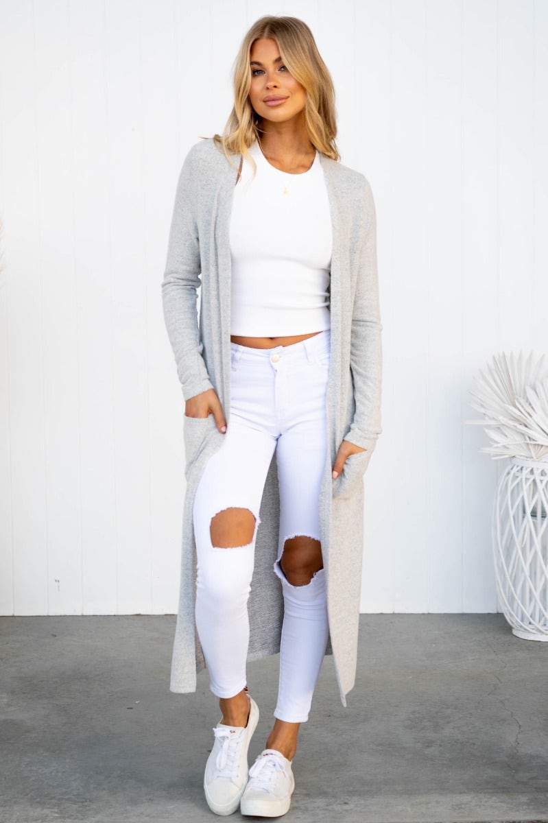 Model wearing Izzy Cardigan with pockets, textured knit, relaxed fit, styled with white outfit and sneakers.